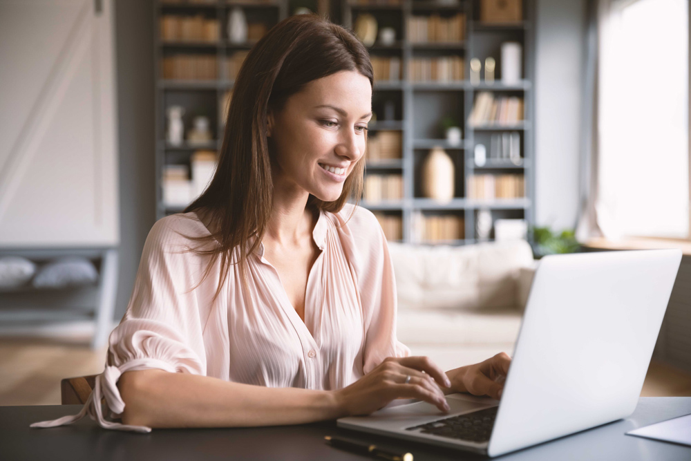 Eine Frau, die am Laptop sitzt und lächelt