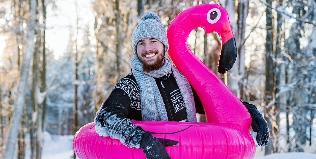 Mann mit Flamingo Schwimmring in einer Winterlandschaft